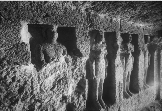 Black & white photo of statues inside a tomb
